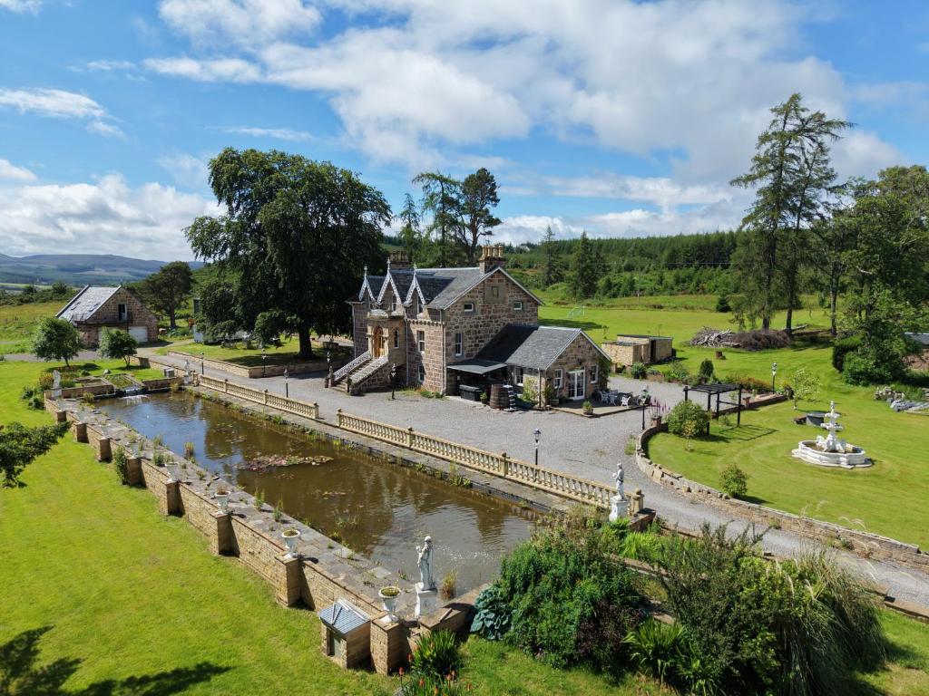 a building next to a river with a bridge at The Doune, Luxury Traditional Country House with hot tub in Inverness