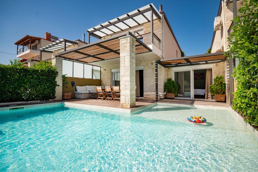 a swimming pool in front of a house at Sunny Exclusive Ena in Hanioti