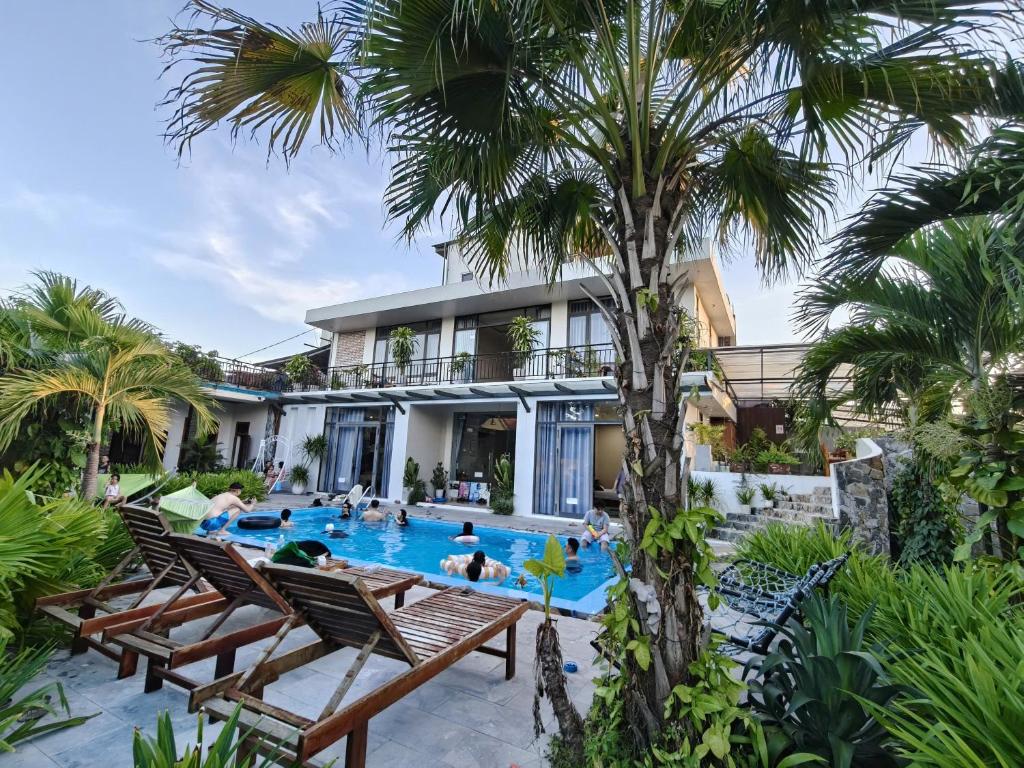 a resort pool with chaise lounge chairs and a palm tree at Hugo Homestay in Phong Nha