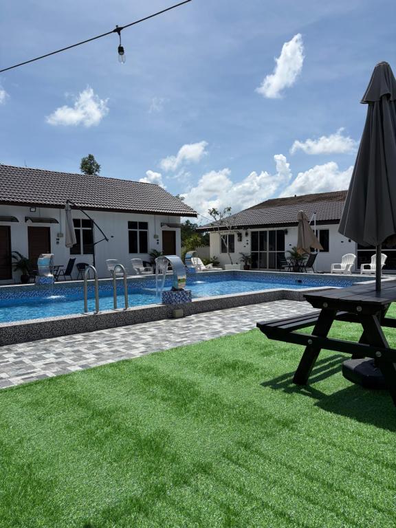 a pool with a picnic table and an umbrella at D' Ehsan Homestay & Chalet in Kuala Terengganu