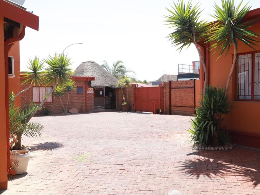 a courtyard with palm trees in front of a building at Oluzizi Guesthouse in Windhoek