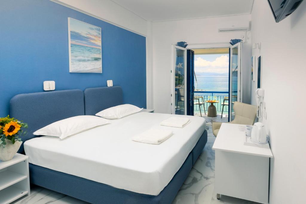 a blue and white bedroom with a bed and a balcony at Hotel Avra in Egina