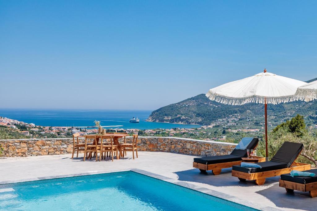 a pool with a table and chairs and an umbrella at Villa Nanoula & Villa Stella Twin Villas Retreat in Skopelos Town