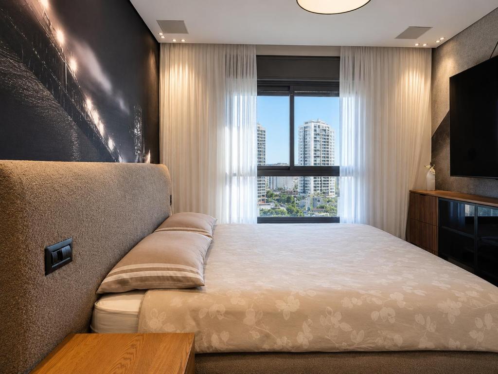 a bedroom with a bed and a large window at דירת החלומות באשדוד in Ashdod