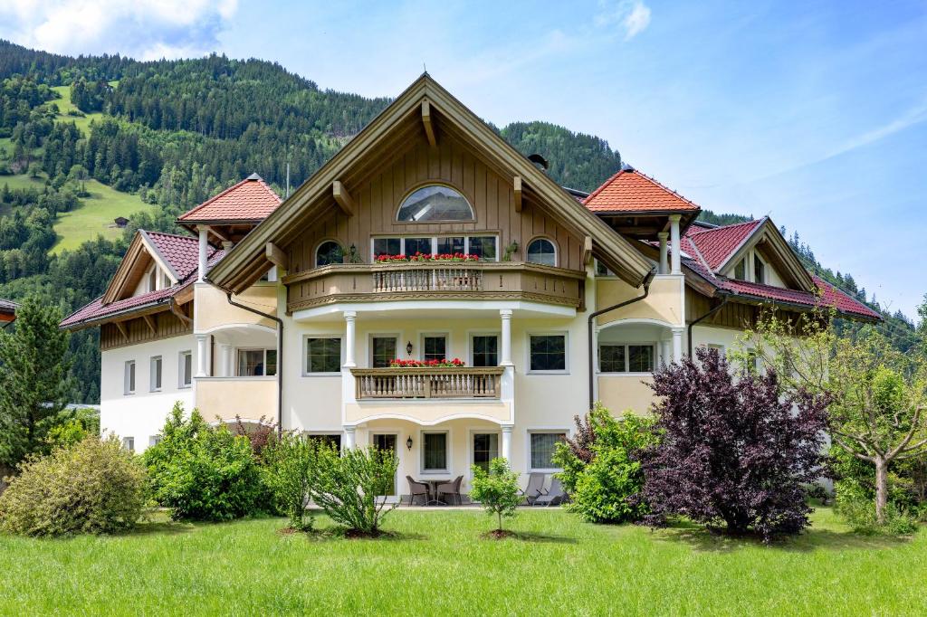 a large house with a balcony on a green field at Alpenresidenz-Sonnwend - Wellness Apartments nahe Zillertal Arena in Zell am Ziller