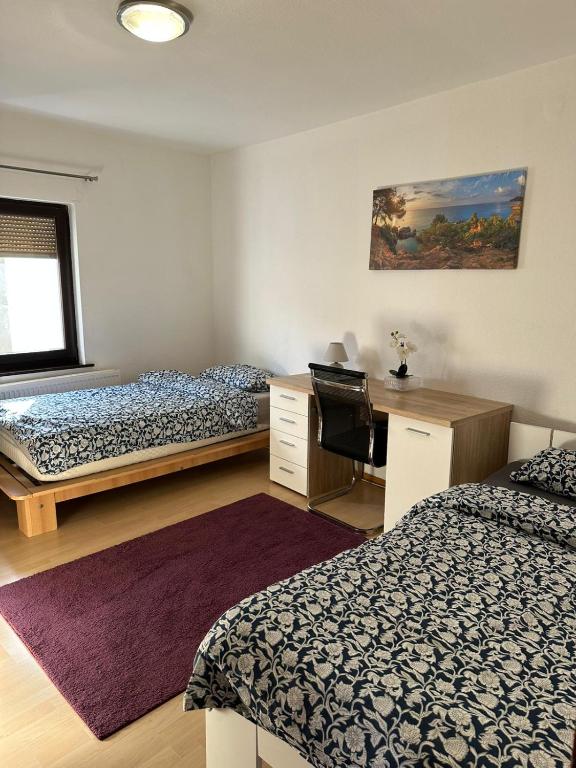 a bedroom with two beds and a desk and a window at Landhaus Butzbach in Butzbach