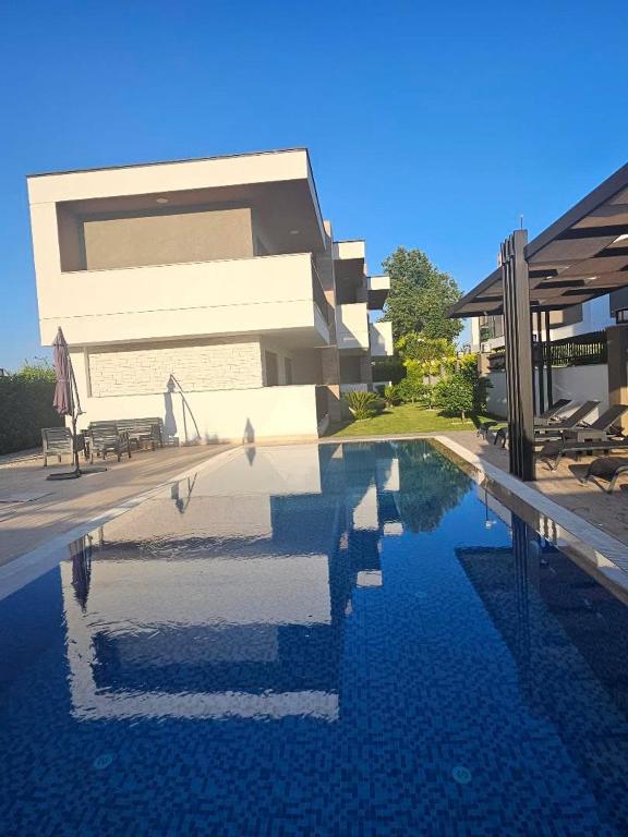 a house with a swimming pool in front of a building at KALİDA APART in Kemer