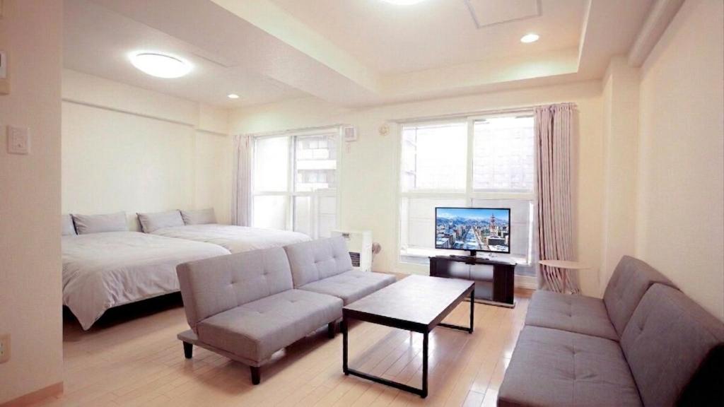 a bedroom with a bed and a couch and a tv at メゾンドアトール in Sapporo