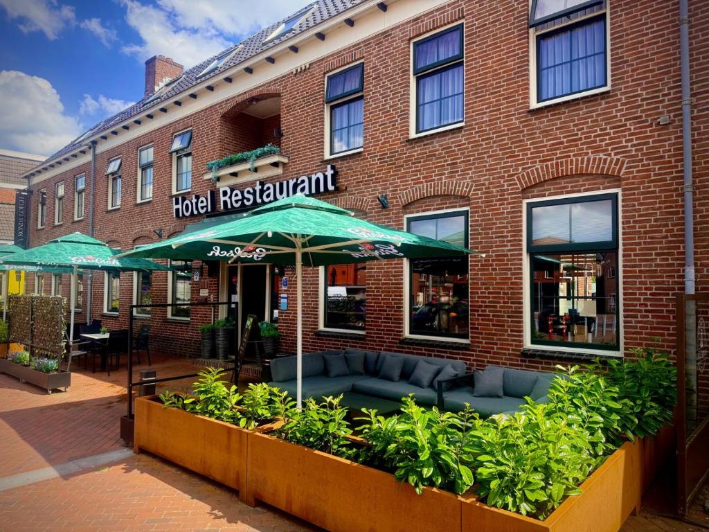 a hotel restaurant with an umbrella in front of a brick building at Hotel Restaurant 't Ronde Loegh in Winschoten