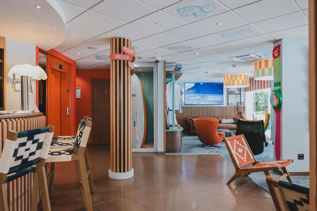 a room with chairs and a table and surfboards at Surf Club Hôtel by Akena - Grande plage in Biarritz