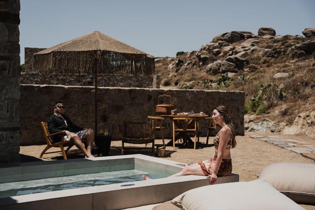 a man and a woman sitting on the edge of a swimming pool at Naxian Rhapsody Luxury Villas in Stelida