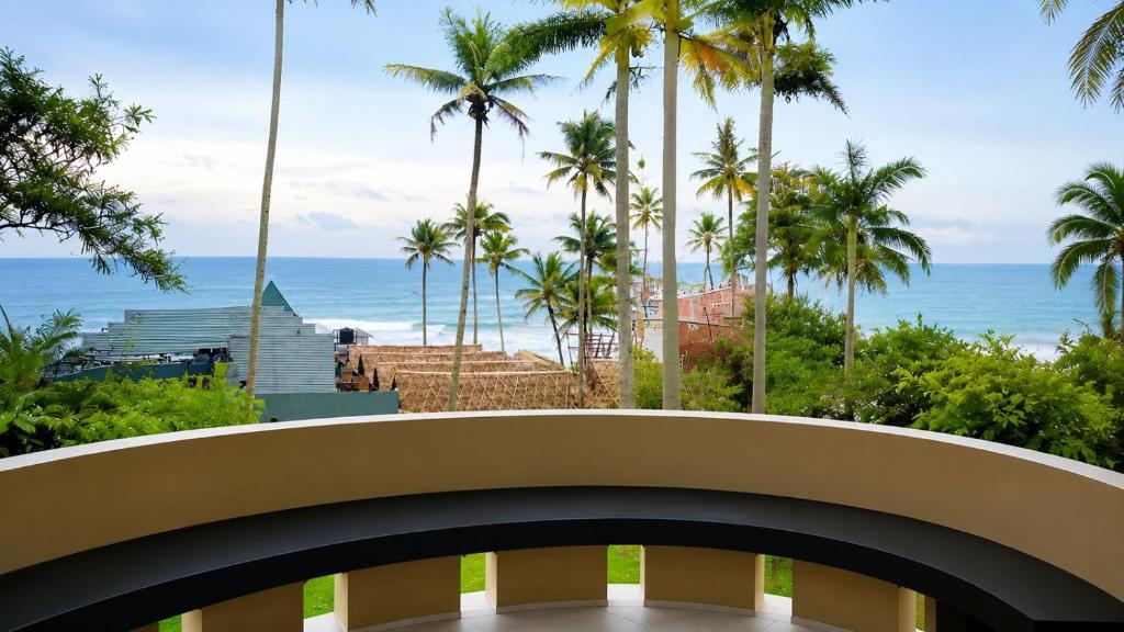 a balcony with a view of the ocean and palm trees at hello varkala beach view balcony resort in Varkala