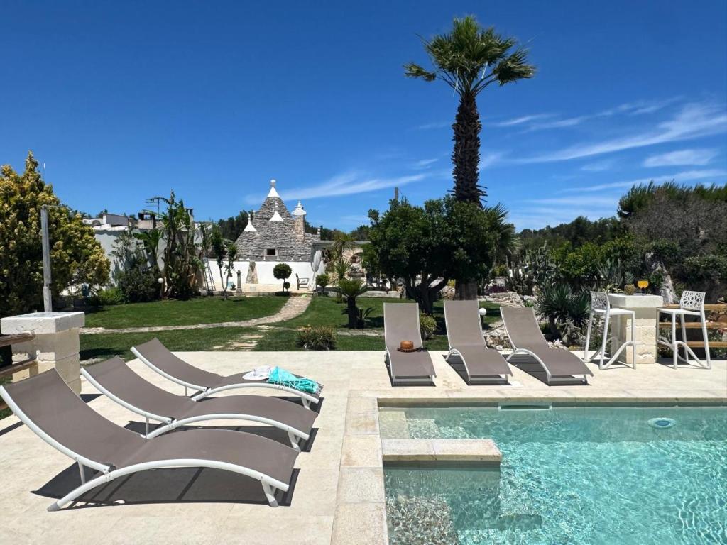 a group of lounge chairs next to a swimming pool at Trullo Suenn - piscina privata in San Michele Salentino