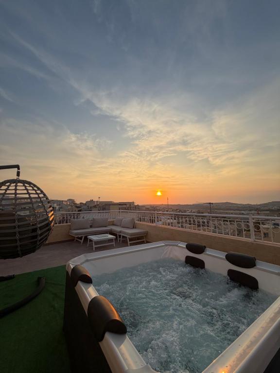 a hot tub on top of a roof with the sunset at Penthouse with Jacuzzi -Sannat in Sannat