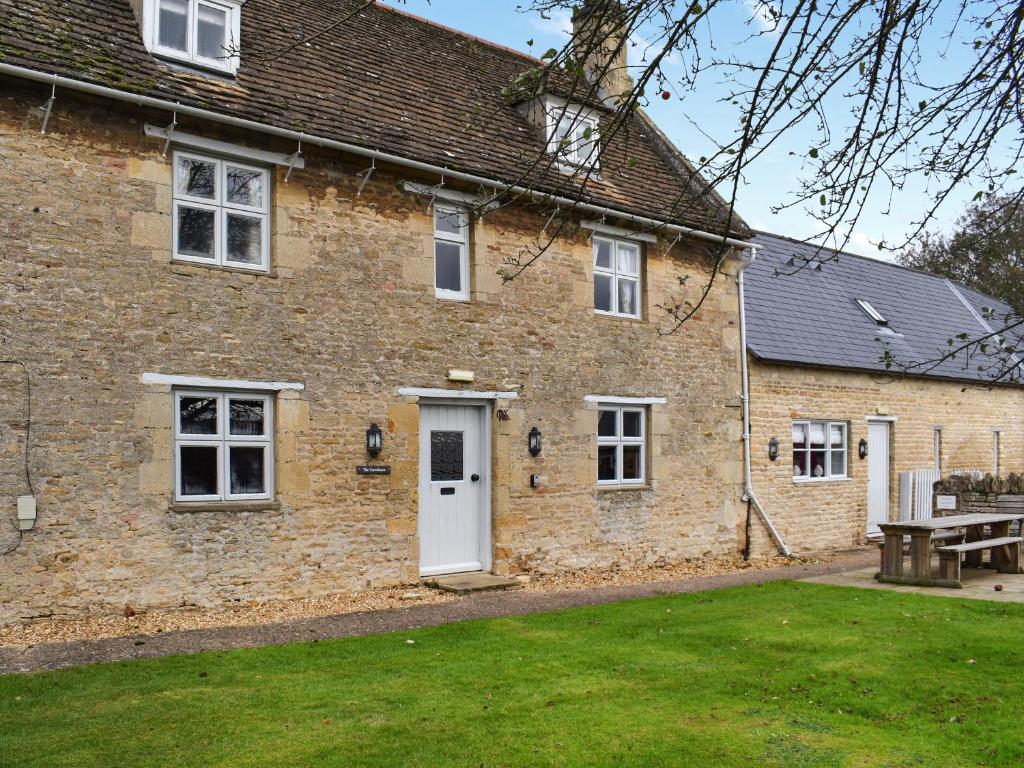 a brick house with a white door and a yard at The Farmhouse - Uk50909 in Thornhaugh