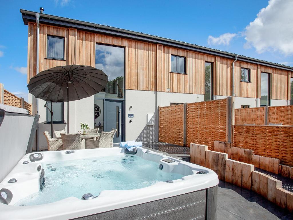 a hot tub on a patio with an umbrella at Bluebell-Uk34613 in Nether Stowey