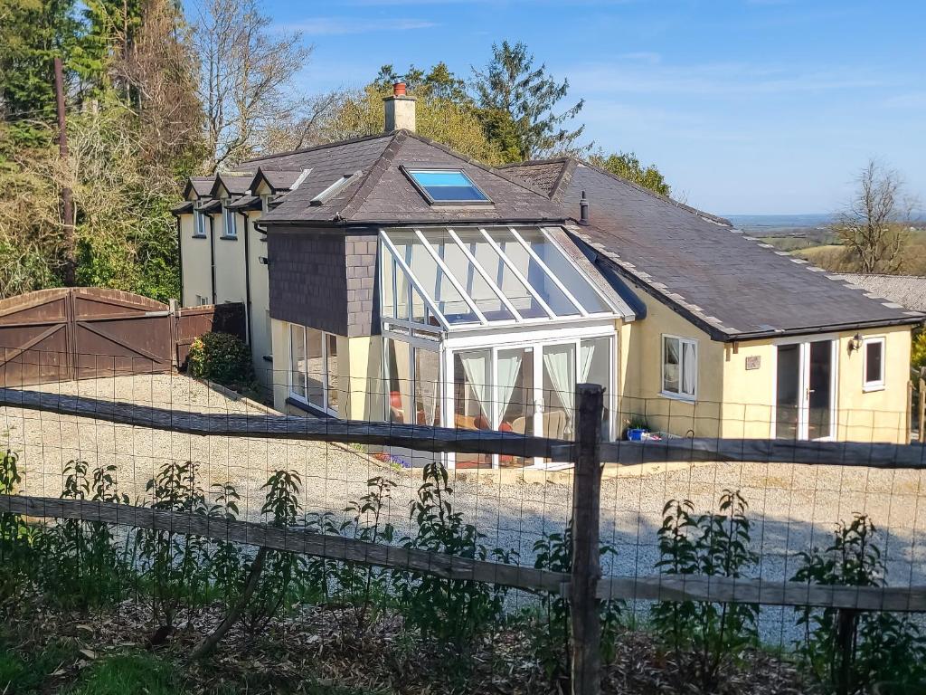 a house with a conservatory and a fence at Heath Hills in Okehampton