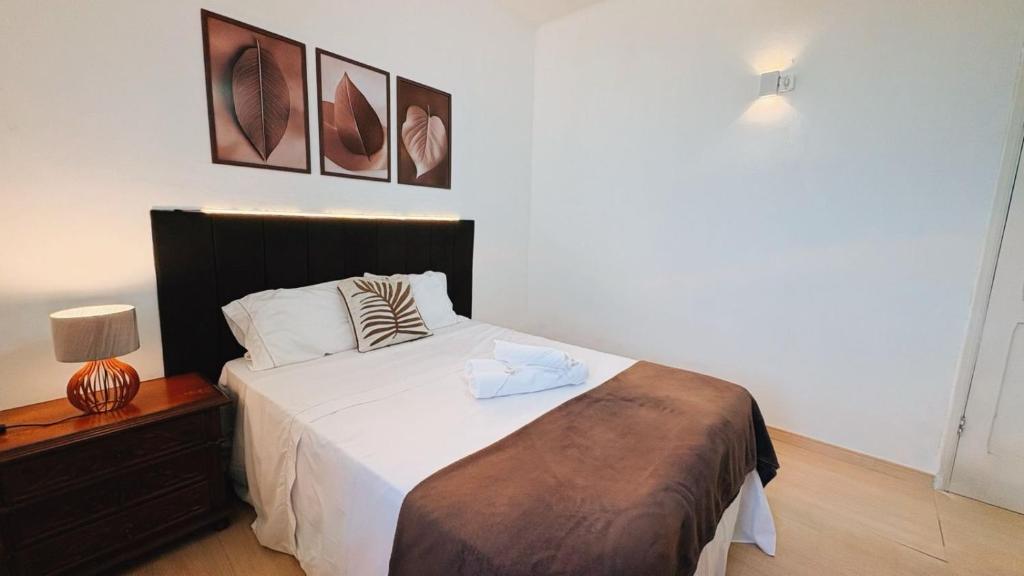 a bedroom with a bed with white sheets and pillows at Suíte no Centro de Caxambu - Poucos metros do Parque in Caxambu