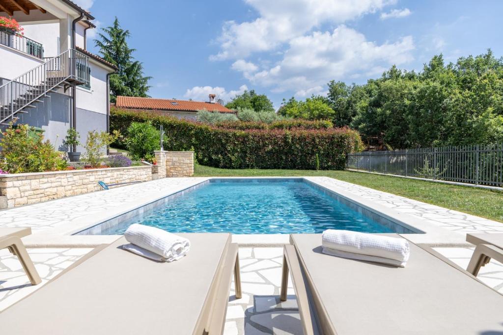 a swimming pool in a yard with two chairs and a swimming pool at Modern Villa Vesna with Private Pool in Jakići