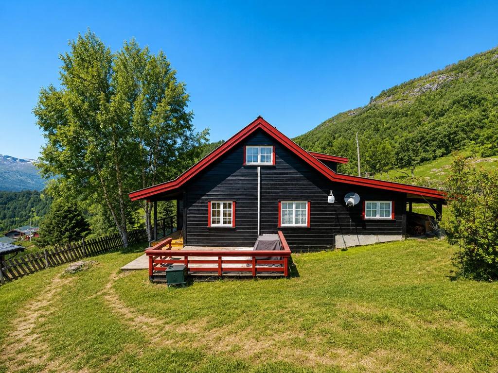 a black house with a red roof on a hill at Charming Cabin Near Hallingskarvet Ski Center, Cozy and Inviting! in Skoro