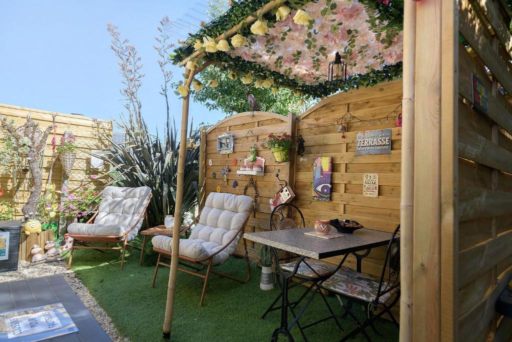 a patio with two chairs and a table and an umbrella at Comme à la maison in Ducey