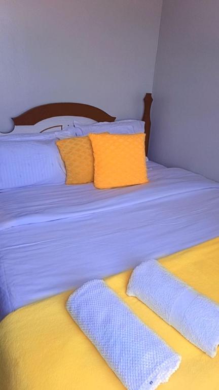 a bed with yellow and white sheets and pillows at Classic in Narok