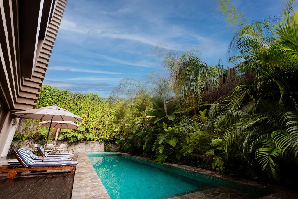 a swimming pool with two chairs and an umbrella at Tintto Hotel in Fortaleza