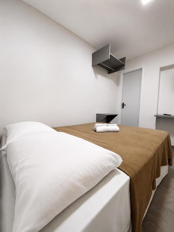 a white bedroom with a bed with a brown blanket at Manaira Suite 02 in João Pessoa