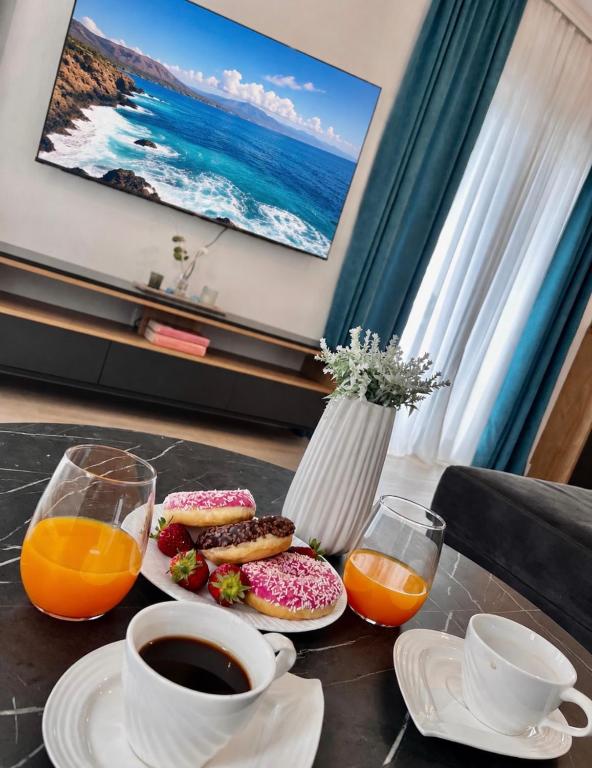 a table with two plates of donuts and orange juice at Kovacevic Apartments in Kotor