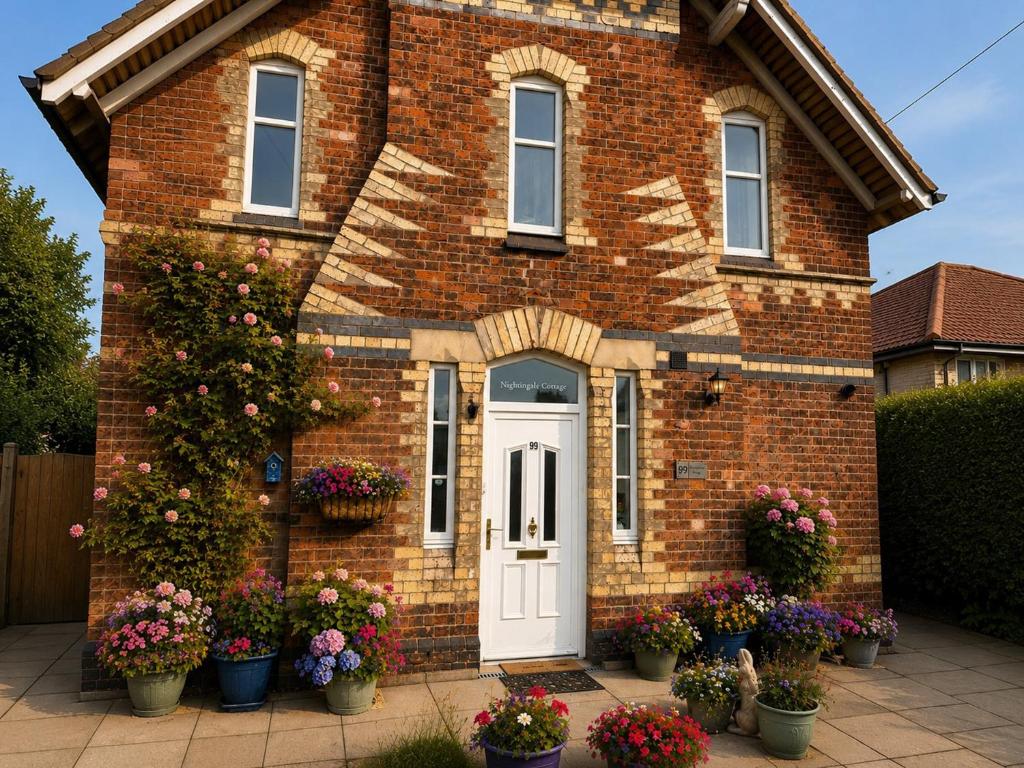 a brick house with potted plants in front of it at Nightingale Cottage in Stafford