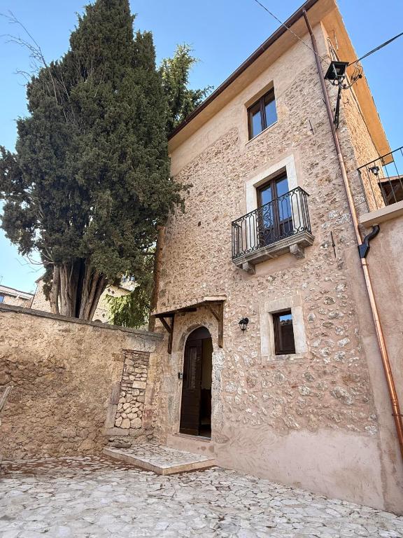 a large stone building with a tree in front of it at Arcem in Calascio