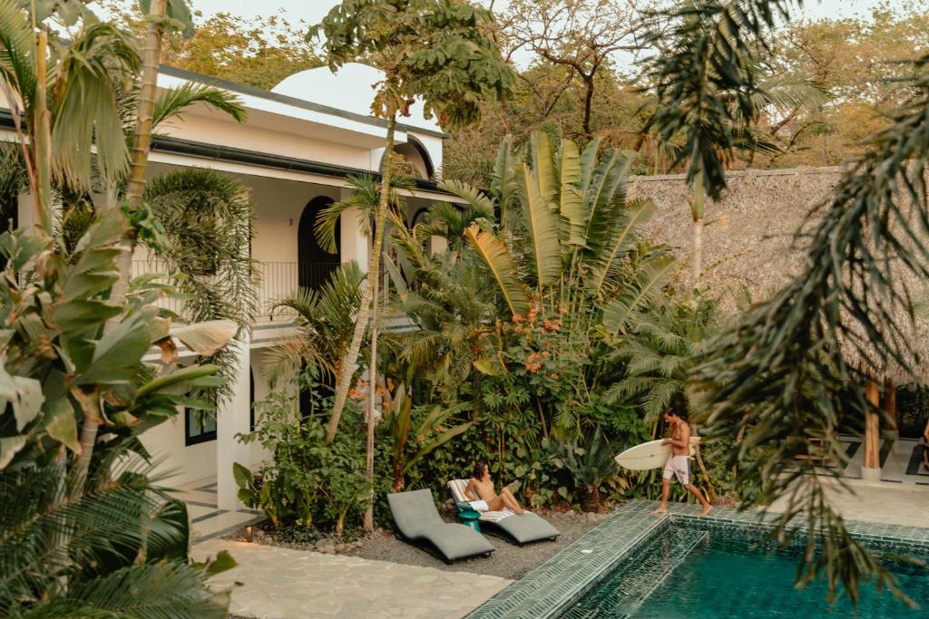 a woman walking by a swimming pool with a surfboard at Domo Nosara Boutique Hotel in Nosara