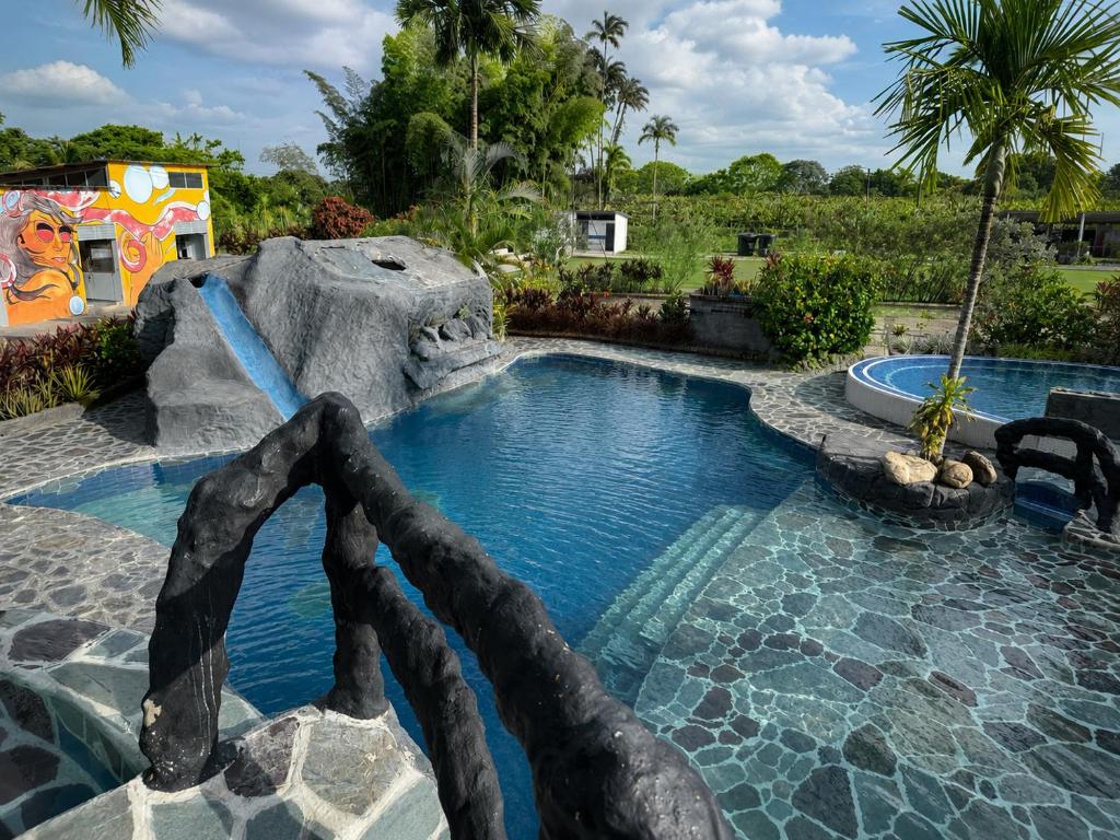 a pool in a backyard with a water slide at Hotel Four20 Zensi - Meta in Lejanías