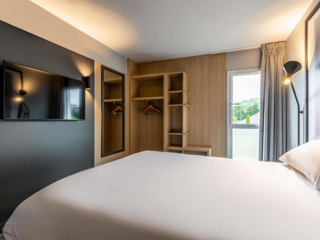 a bedroom with a large white bed and a window at ibis Issoire in Issoire