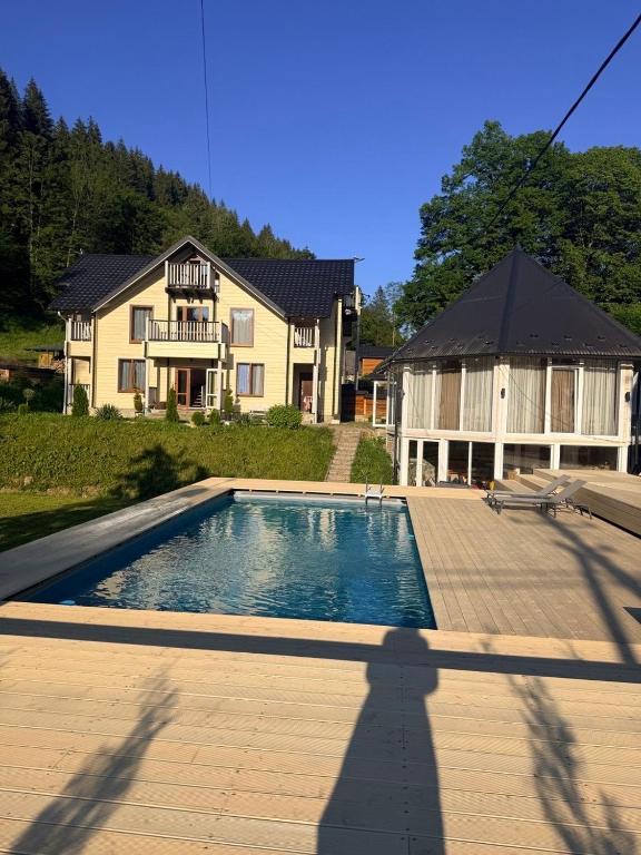 a house with a swimming pool in front of a house at Кільце Карпат in Verkhniy Yasenov