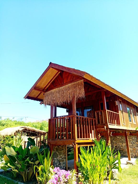 a large wooden house with a grass roof at Cozy cove hut in Pulau Sarang