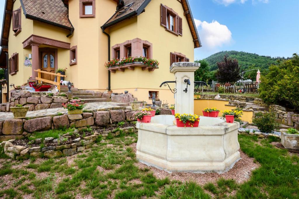 a house with a fountain in front of a yard at Chambre d'hôte La Châtelaine in Walbach