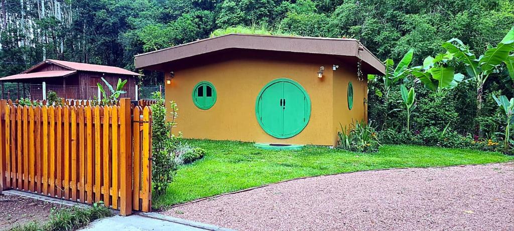 a small house with a green door in a yard at Cabana Refúgio do Hobbit-Gramado @refugiodohobbit in Gramado