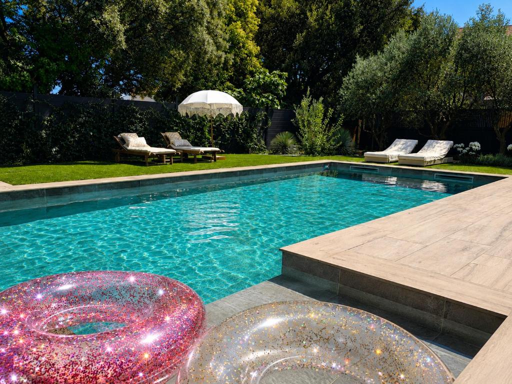 a swimming pool with two chairs and a table at Suite neuve piscine privée Les Charmettes in La Ciotat