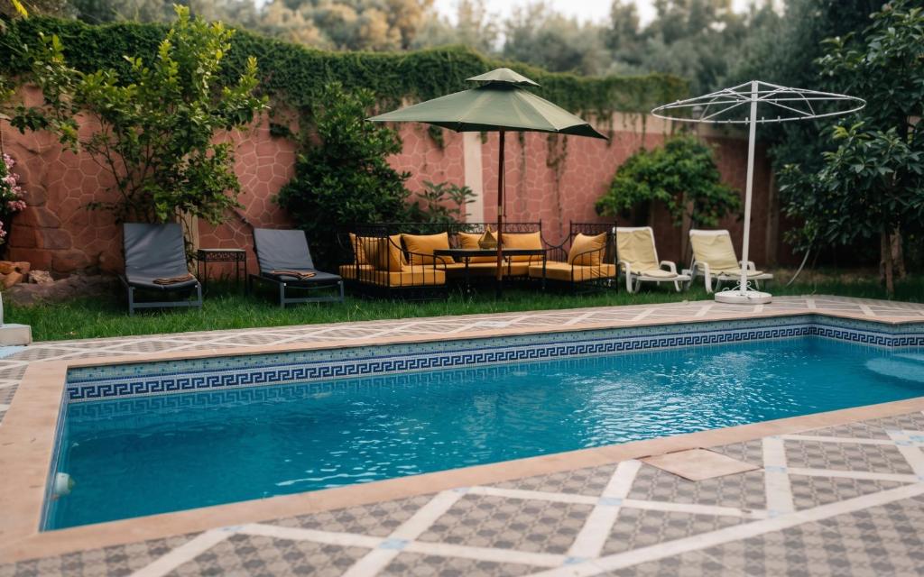 a swimming pool with chairs and a table and an umbrella at Villas khadija in Marrakesh