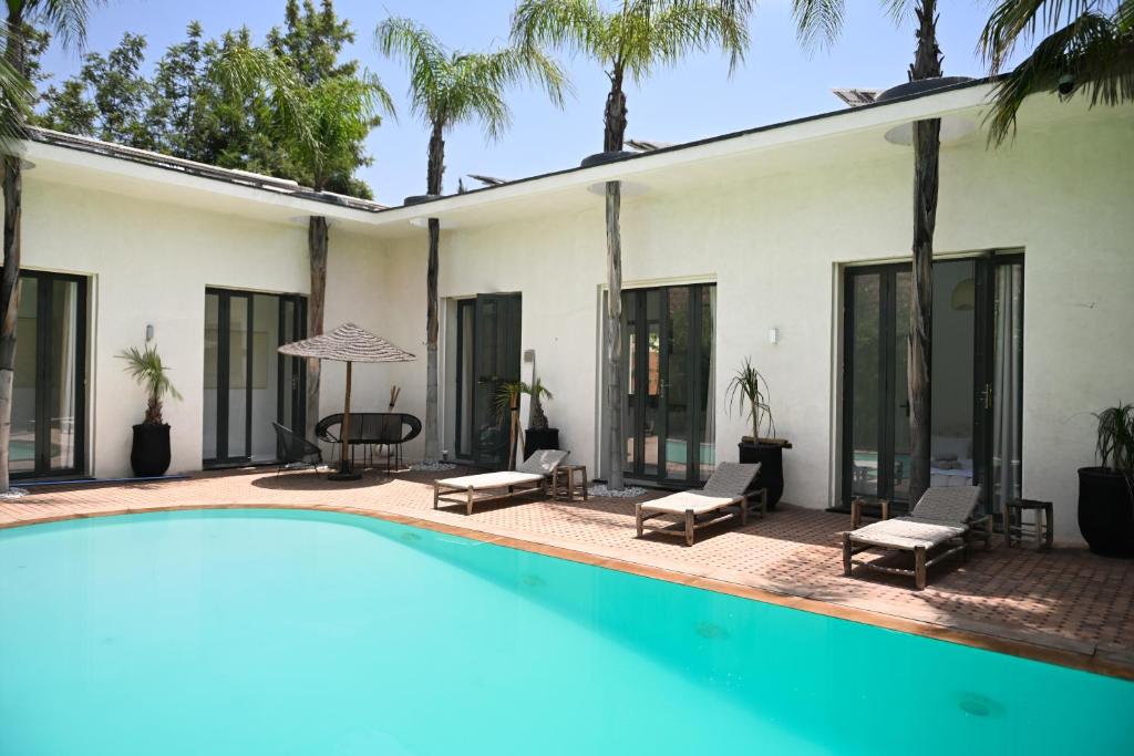 a villa with a swimming pool and palm trees at Villa Marrakech ,Piscine Privée & Luxe Authentique in El Aggada