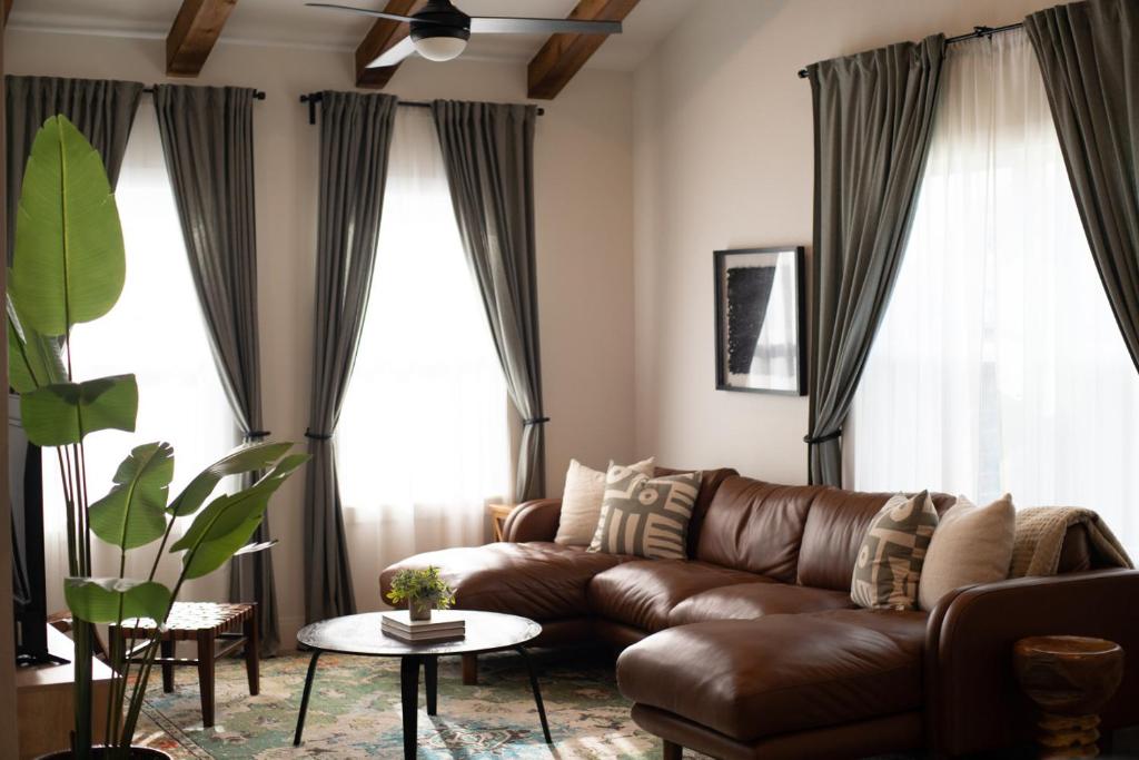 a brown leather couch in a living room with windows at Orion B, Vaulted Ceilings, Pool, Bunk Room in Port Isabel