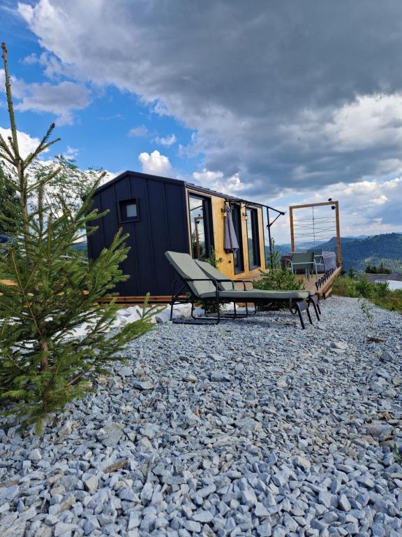 a black tiny house with a swing and a bench at Veya Cabins Apuseni in Trifeşti