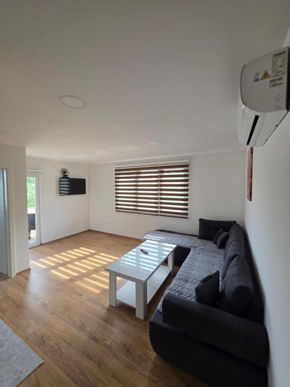 a living room with a black couch and a table at Apartmani gradina Tuzla in Tuzla