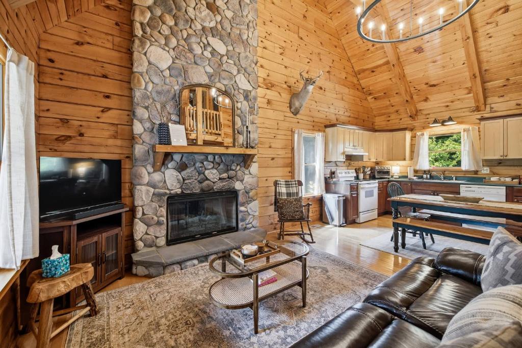 a living room with a stone fireplace in a log cabin at County Line Cabin in Woodland Beach