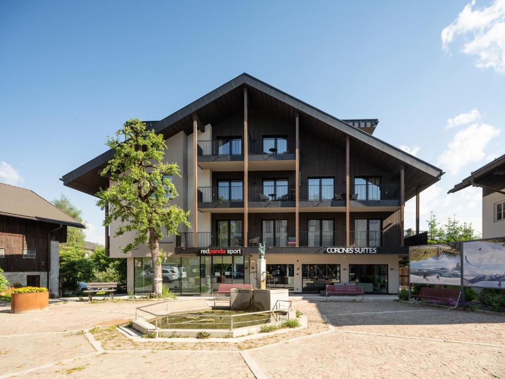 a large building with a tree in front of it at Corones Suites - Dolomites Residence in Valdaora