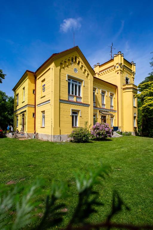a large yellow building on a grass field at Zámeček Rozkoš in Střížovice