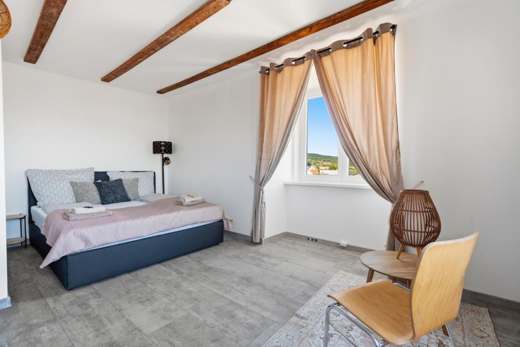 a bedroom with a bed and a chair and a window at Appartement im Schloßhof in Rechnitz