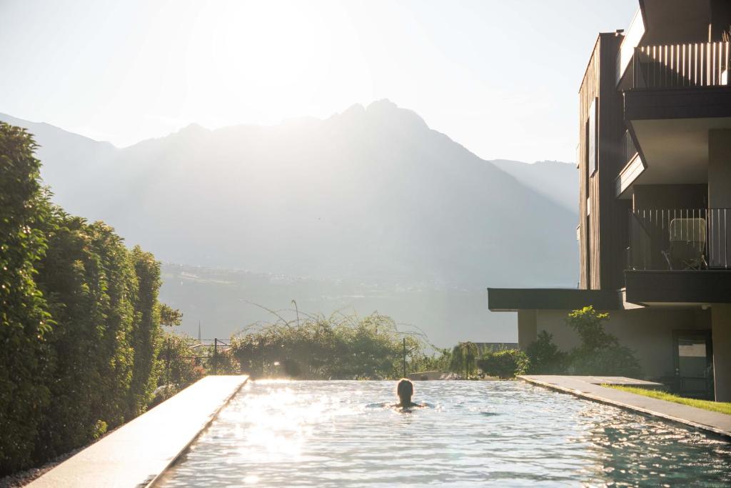 a person swimming in a pool in a building at Garni-Hotel Der Forsterhof in Lagundo