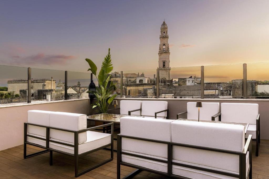 a restaurant with white chairs and a table and a clock tower at Tivoli Palazzo 1880 Lecce Hotel in Lecce